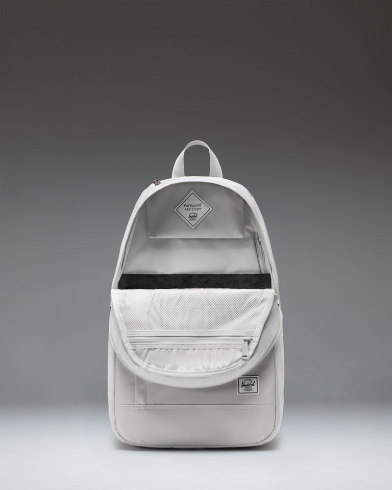 A light grey Herschel Seymour Backpack in the color Metal, featuring dual side pockets and the signature brand logo on the bottom left.
