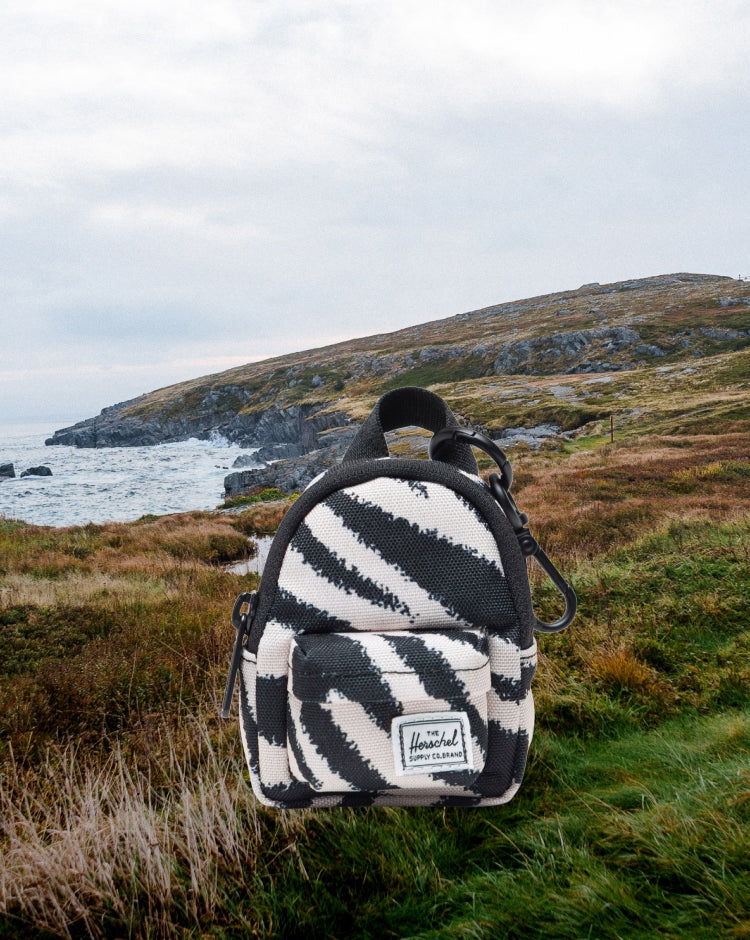 Herschel Supply Co. Classic Backpack Bag Charm in a black and white zebra print pattern, designed as a miniature accessory with a metal clip.