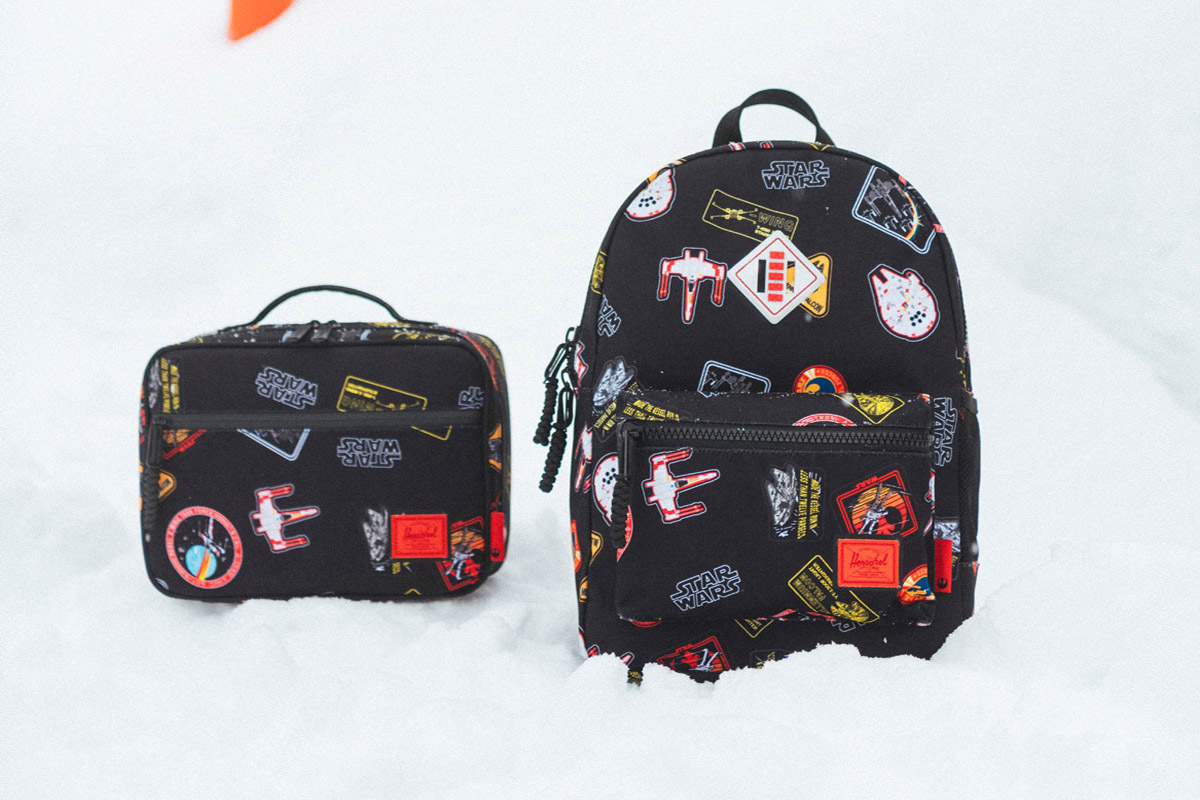 a pop quiz lunch box and a heritage backpack sit on a snowy background