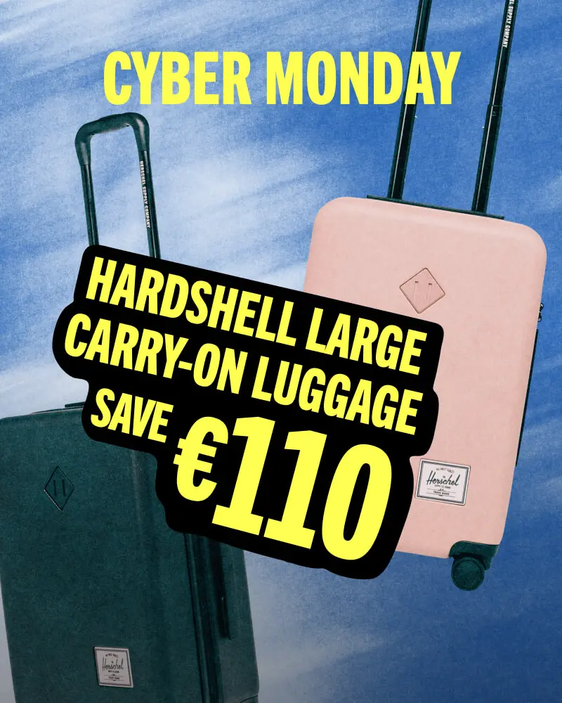 A black & ash rose Herschel Heritage Hardshell Large Carry On suitcases against a blue background with the title CYBER MONDAY informing that Hardshell Large Carry-On Luggage is 40% off.