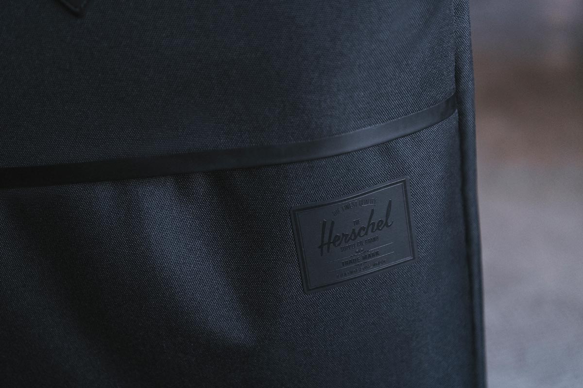 The front zippered pocket of the Highland Luggage Large with the tonal black Herschel Supply Company label